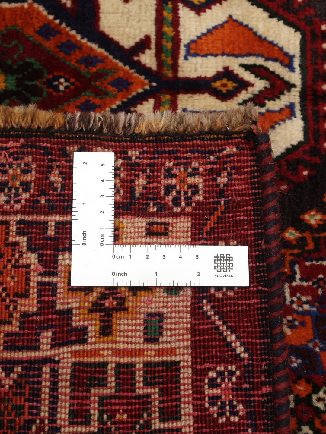 A hand-knotted Qashqai rug from the Middle East featuring a vibrant red field and geometric medallion patterns.