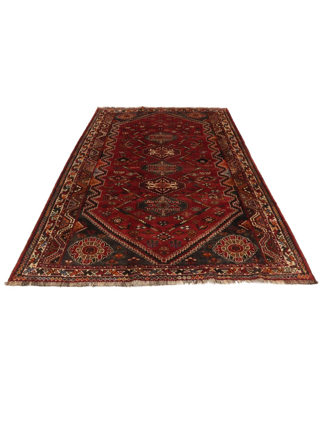 A hand-knotted Ghashghai rug from the Middle East featuring a vibrant red and dark-blue geometric design.