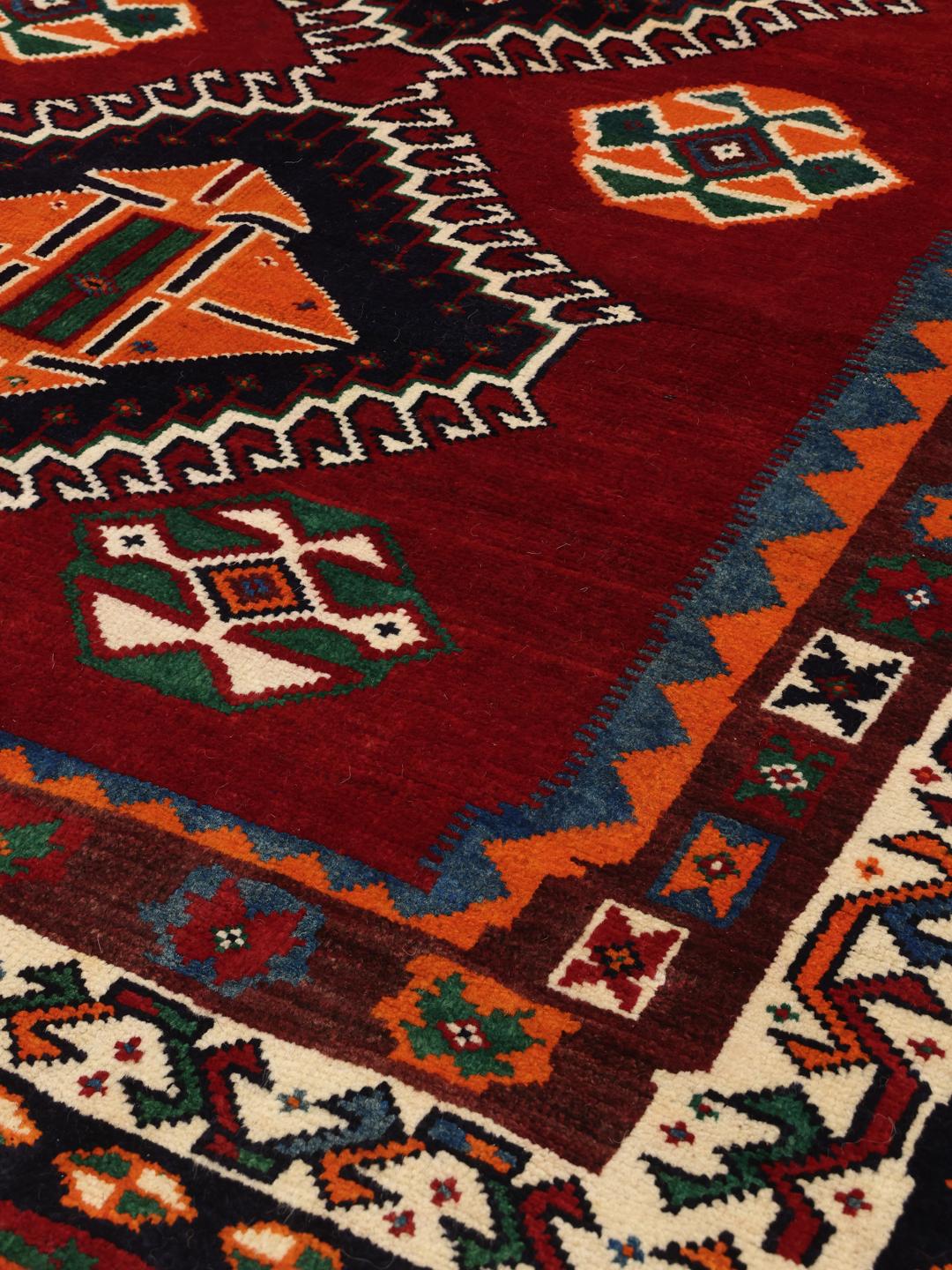 Hand-knotted Qashqai rug from the Middle East with a red field and geometric patterns
