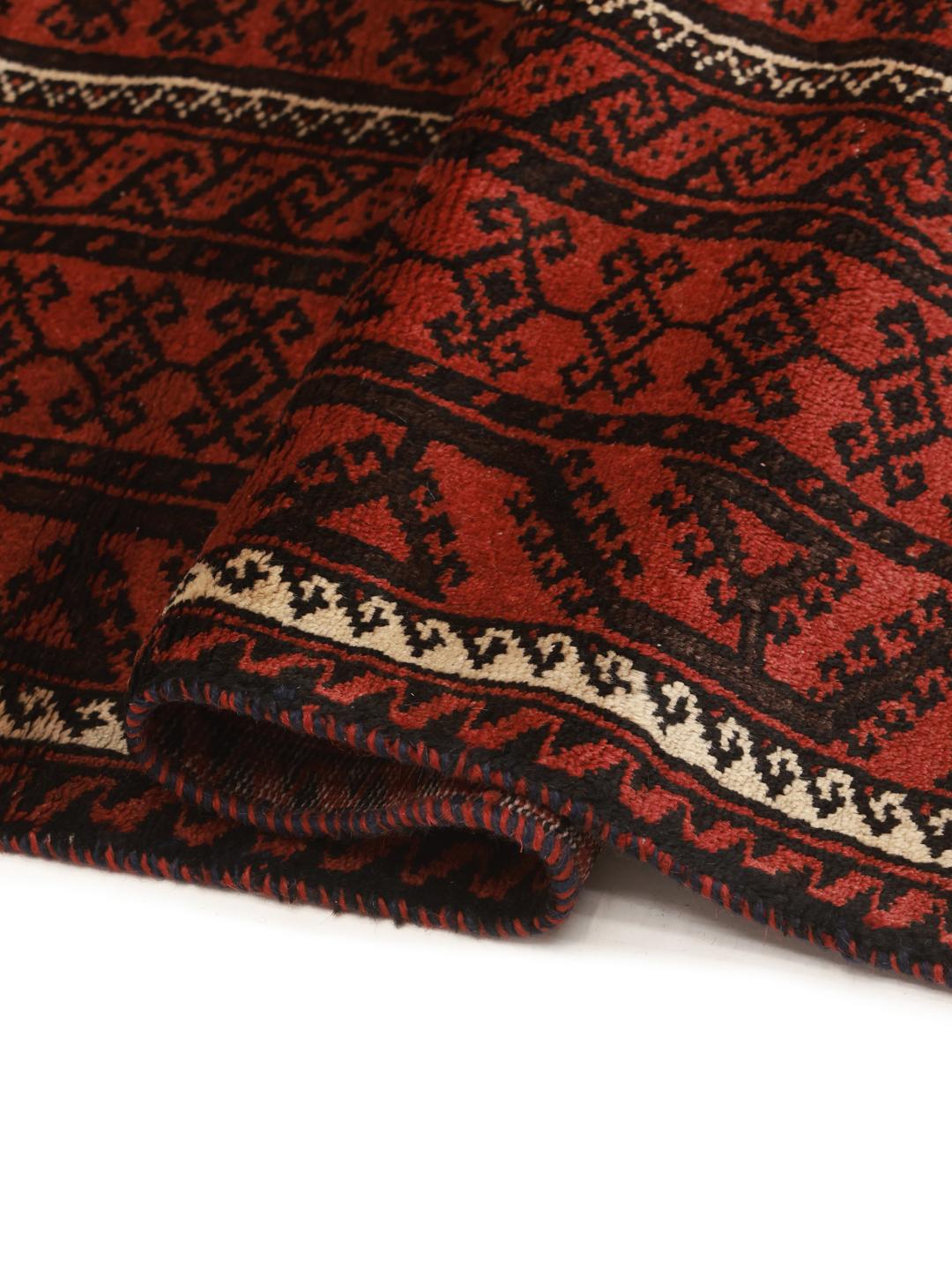 A hand-knotted Baluch rug with a dark-red field and geometric motifs from the Middle East.