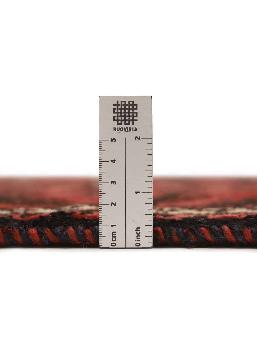 A hand-knotted Baluch rug with a dark-red field and geometric motifs from the Middle East.