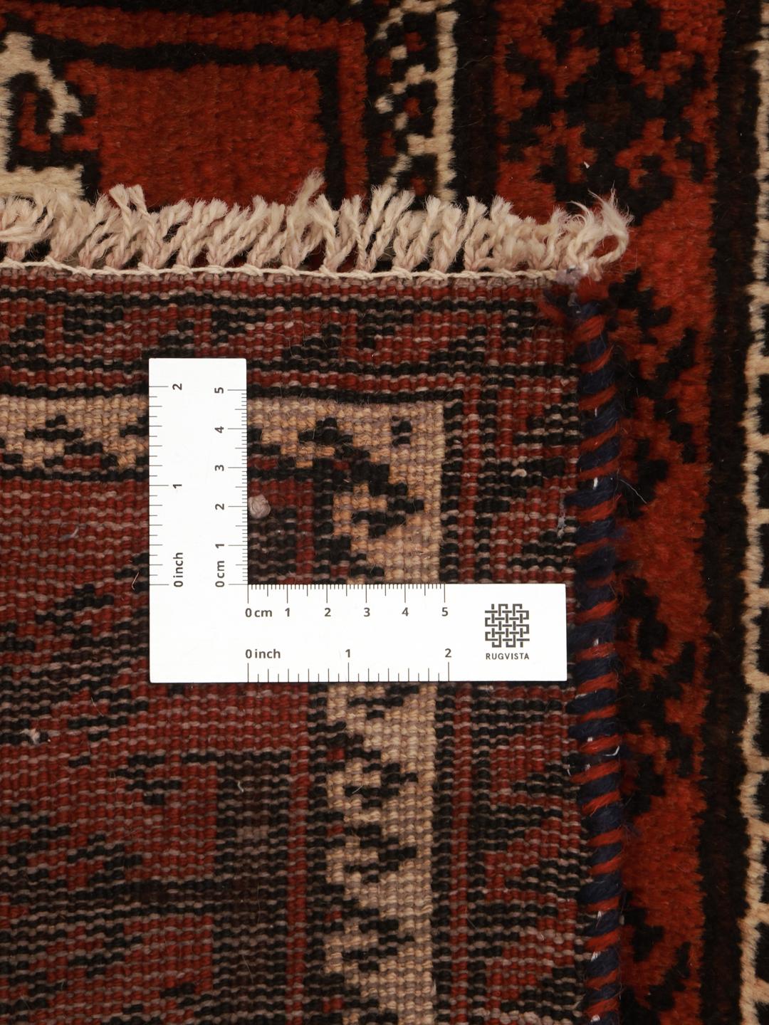 A hand-knotted Baluch rug with a dark-red field and geometric motifs from the Middle East.