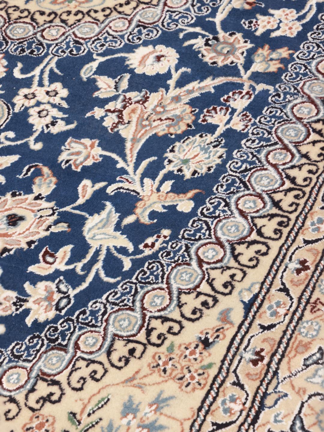 Hand-knotted Nain rug with a deep blue medallion and cream background from the Middle East