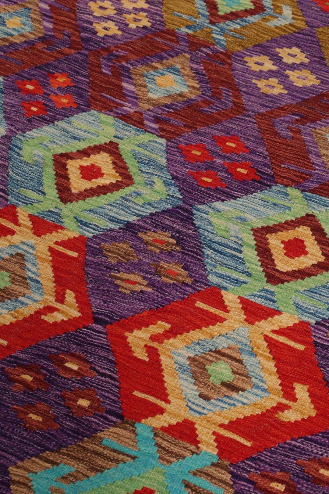 Een handgeweven, veelkleurig Afghaans Kelim-tapijt met geometrische motieven.