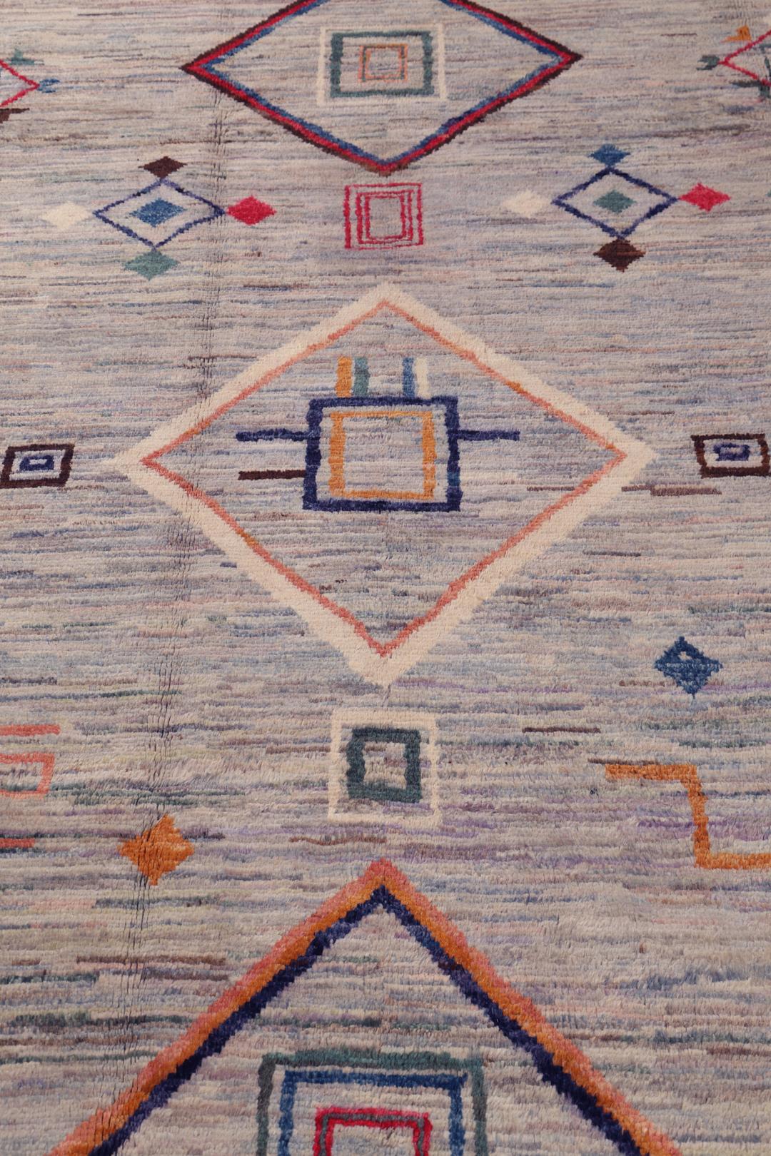 A large hand-knotted Afghan Berber rug with geometric motifs on a blue field.