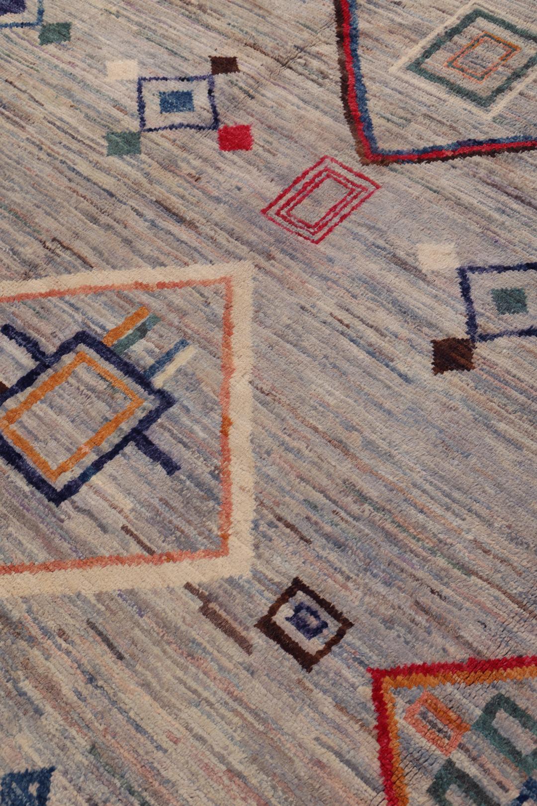 A large hand-knotted Afghan Berber rug with geometric motifs on a blue field.