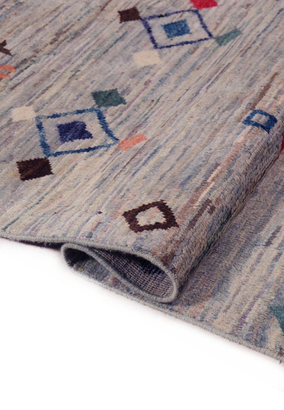 A large hand-knotted Afghan Berber rug with geometric motifs on a blue field.