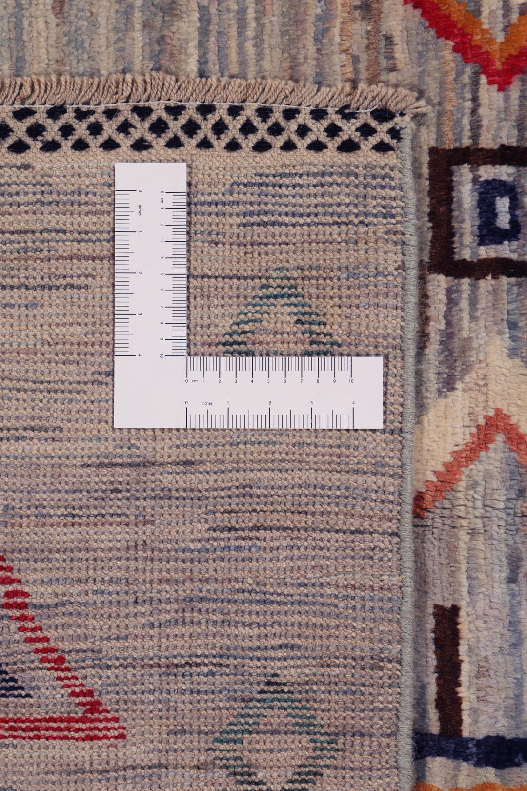 A large hand-knotted Afghan Berber rug with geometric motifs on a blue field.