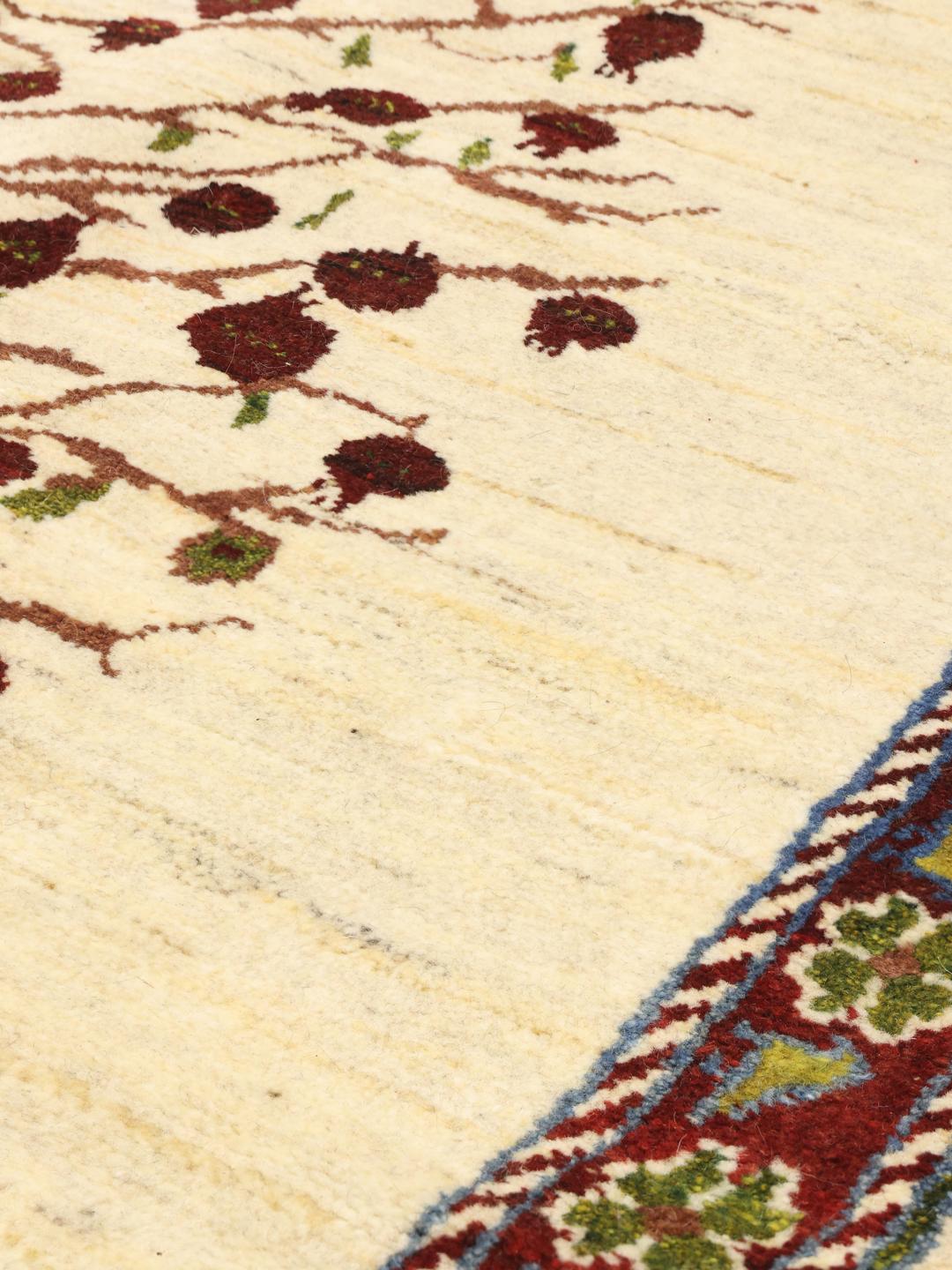 Handgeknoopt Loribaft-tapijt met een levensboommotief in beige, rode en groene tinten.