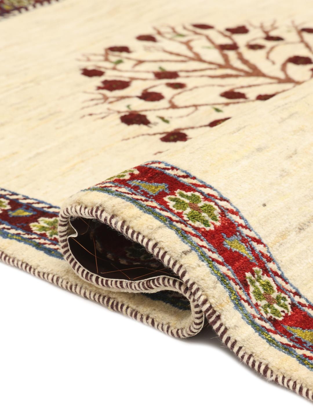 Handgeknoopt Loribaft-tapijt met een levensboommotief in beige, rode en groene tinten.