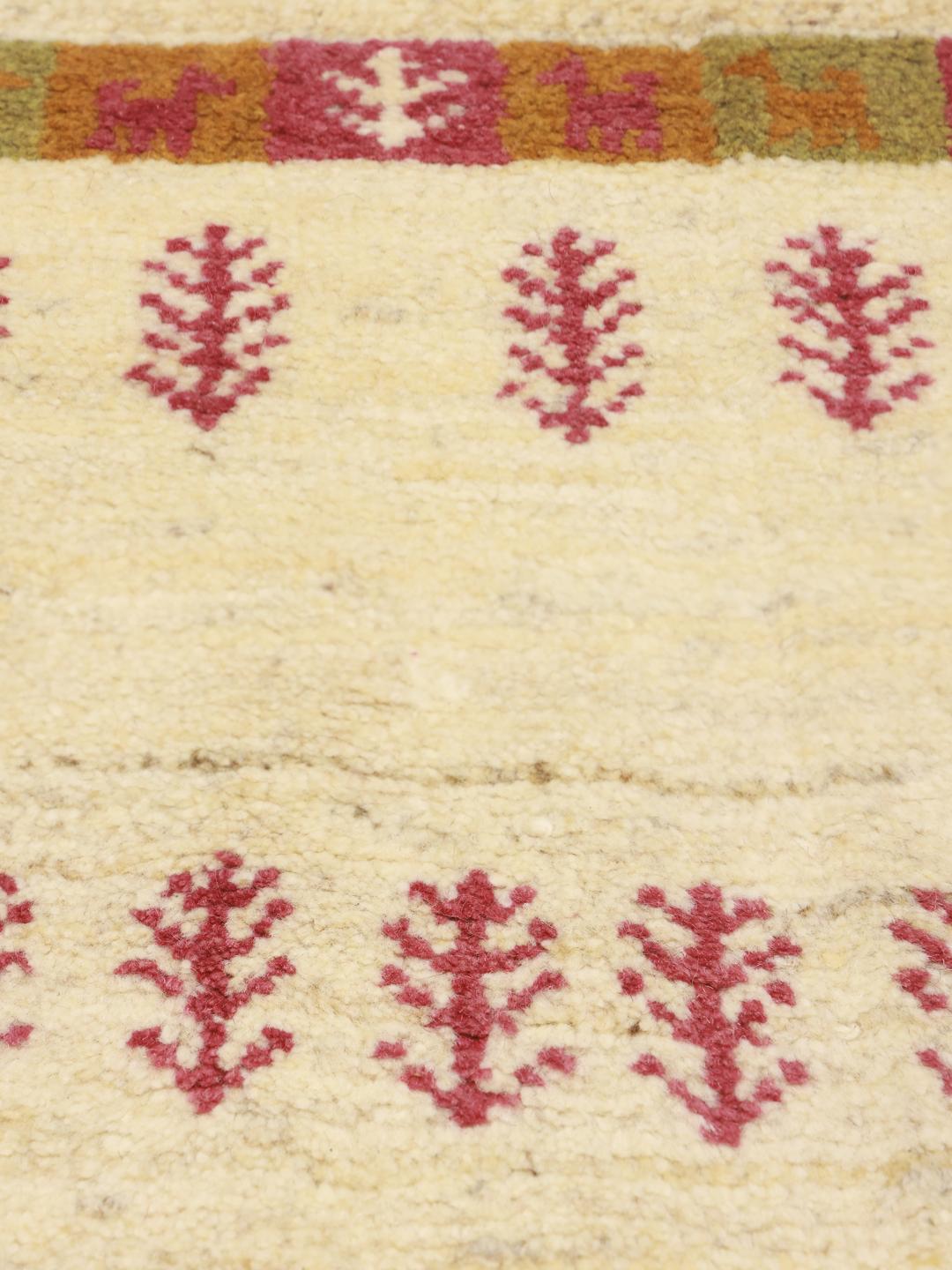Een klein rechthoekig Gabbeh-tapijt met een beige veld en rode boommotieven, afkomstig uit het Midden-Oosten.