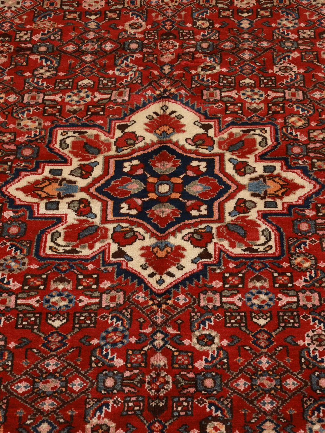 Hand-knotted Hosseinabad rug with a rich red field and decorative floral patterns