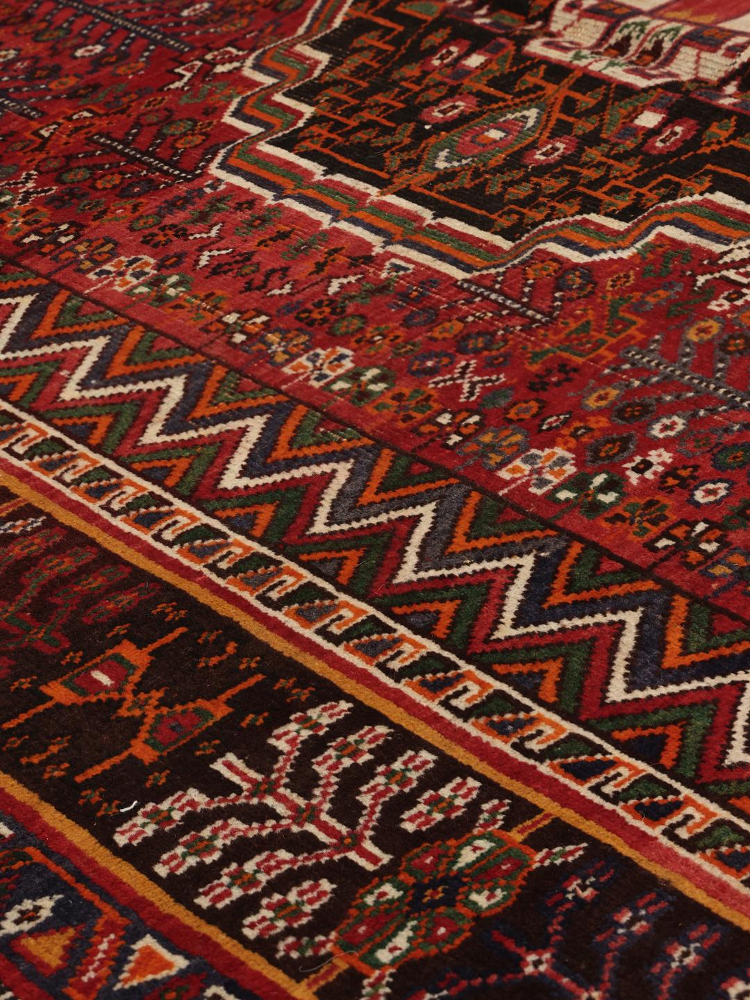 Hand-knotted Shiraz rug from the Middle East featuring a vibrant red field with geometric motifs.
