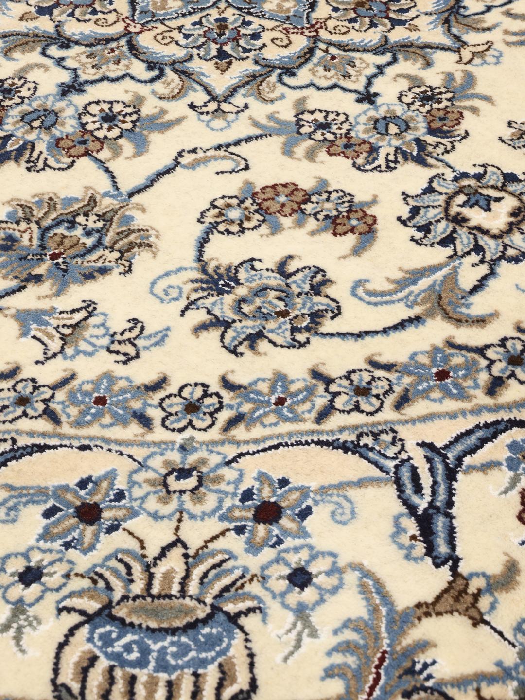 Een rond, handgeknoopt Nain tapijt met verfijnde bloemmotieven in blauw en beige.