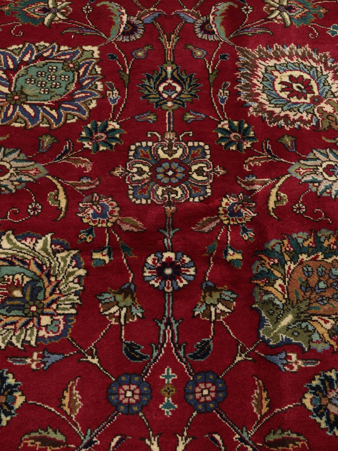 Een groot rechthoekig Tabriz-tapijt uit het Midden-Oosten met een rood veld en een blauwe rand.