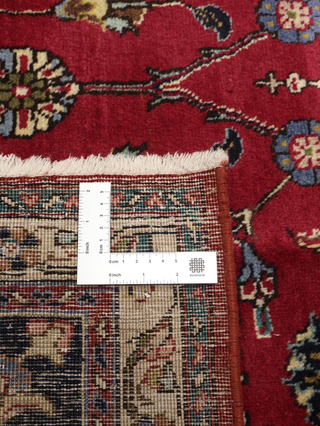 Een groot rechthoekig Tabriz-tapijt uit het Midden-Oosten met een rood veld en een blauwe rand.