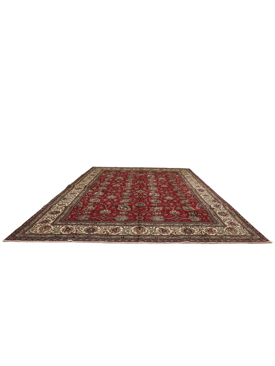 Een groot, handgeknoopt Tabriz-tapijt met een dieprood veld en ingewikkelde bloempatronen.