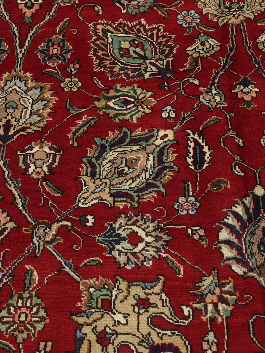 Een groot, handgeknoopt Tabriz-tapijt met een dieprood veld en ingewikkelde bloempatronen.