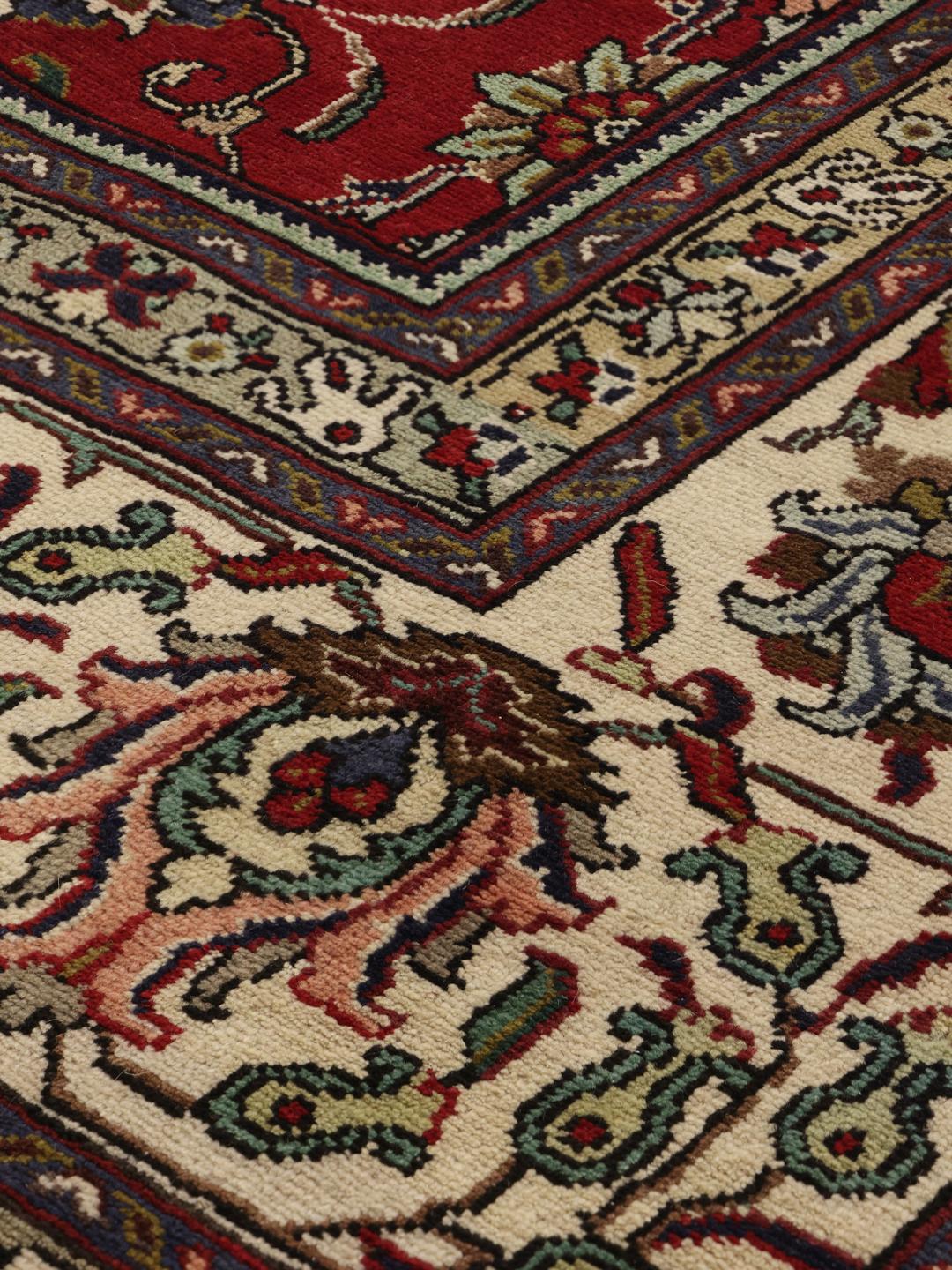 Een groot, handgeknoopt Tabriz-tapijt met een dieprood veld en ingewikkelde bloempatronen.