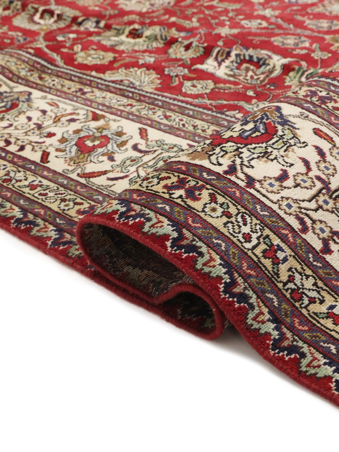 Een groot, handgeknoopt Tabriz-tapijt met een dieprood veld en ingewikkelde bloempatronen.