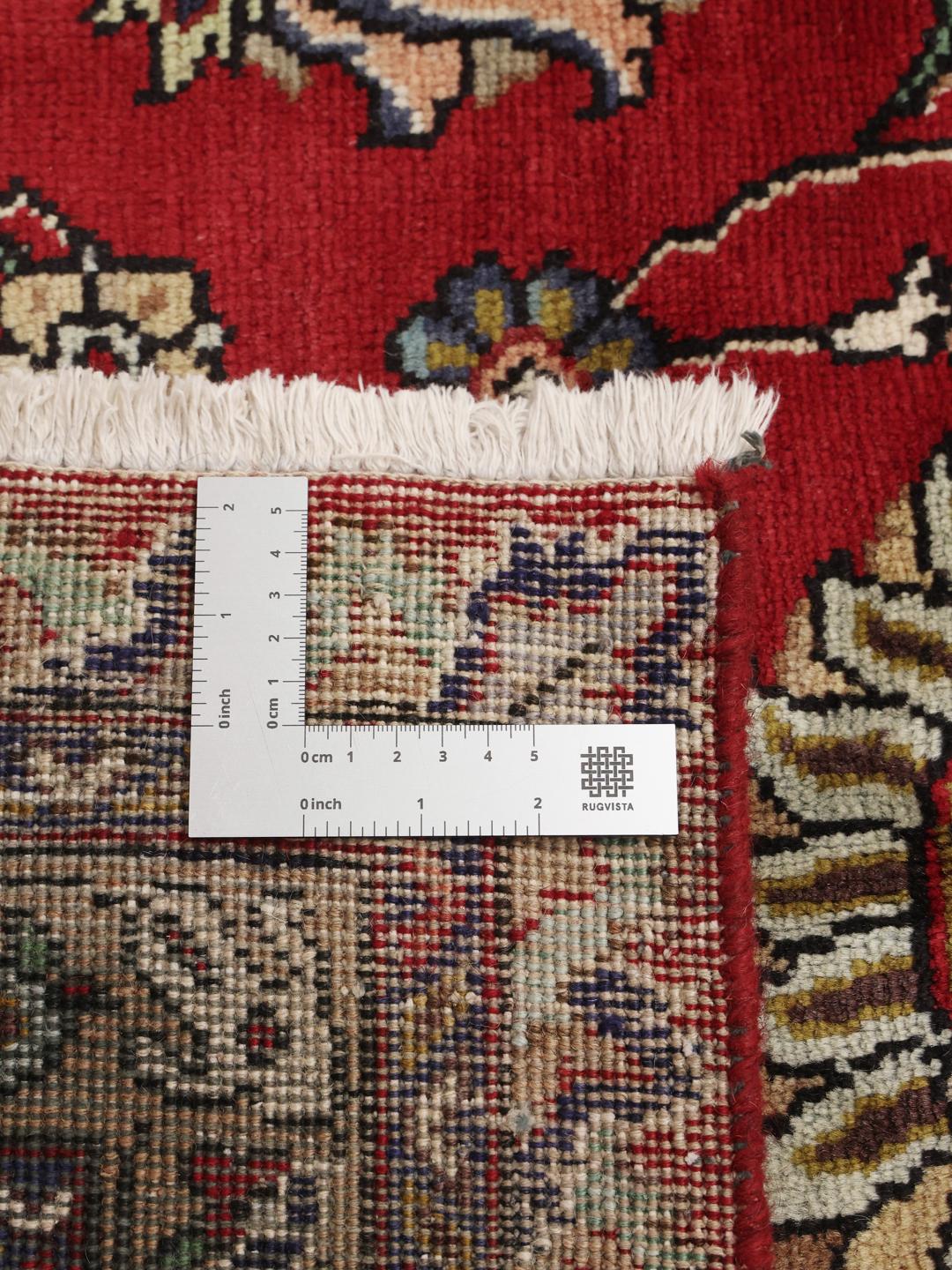 Een groot, handgeknoopt Tabriz-tapijt met een dieprood veld en ingewikkelde bloempatronen.