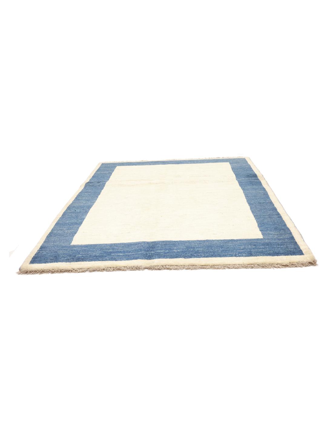 Tapis Gabbeh noué à la main venant du Moyen-Orient avec un champ beige et une bordure bleu foncé.