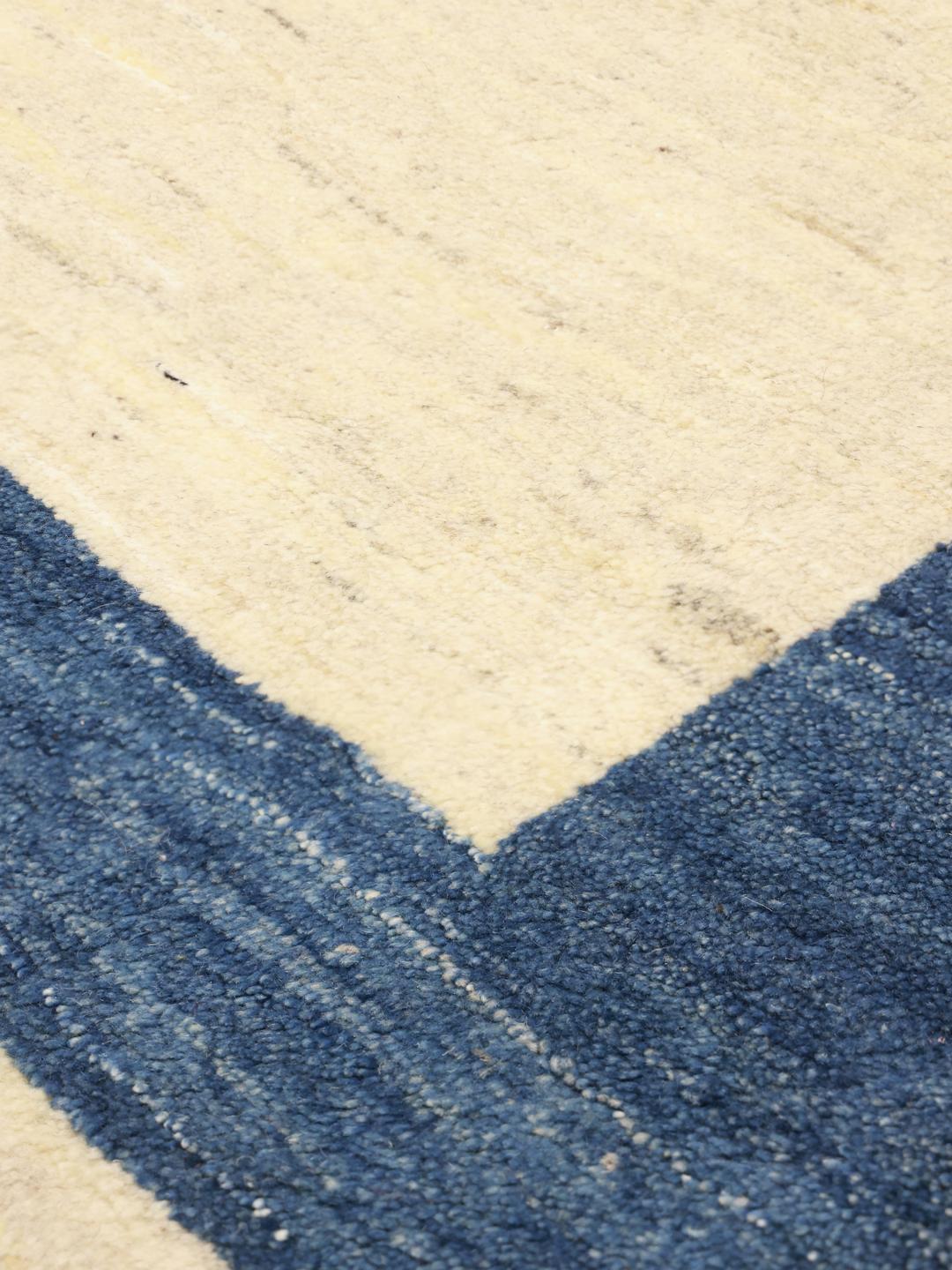 Tapis Gabbeh noué à la main venant du Moyen-Orient avec un champ beige et une bordure bleu foncé.