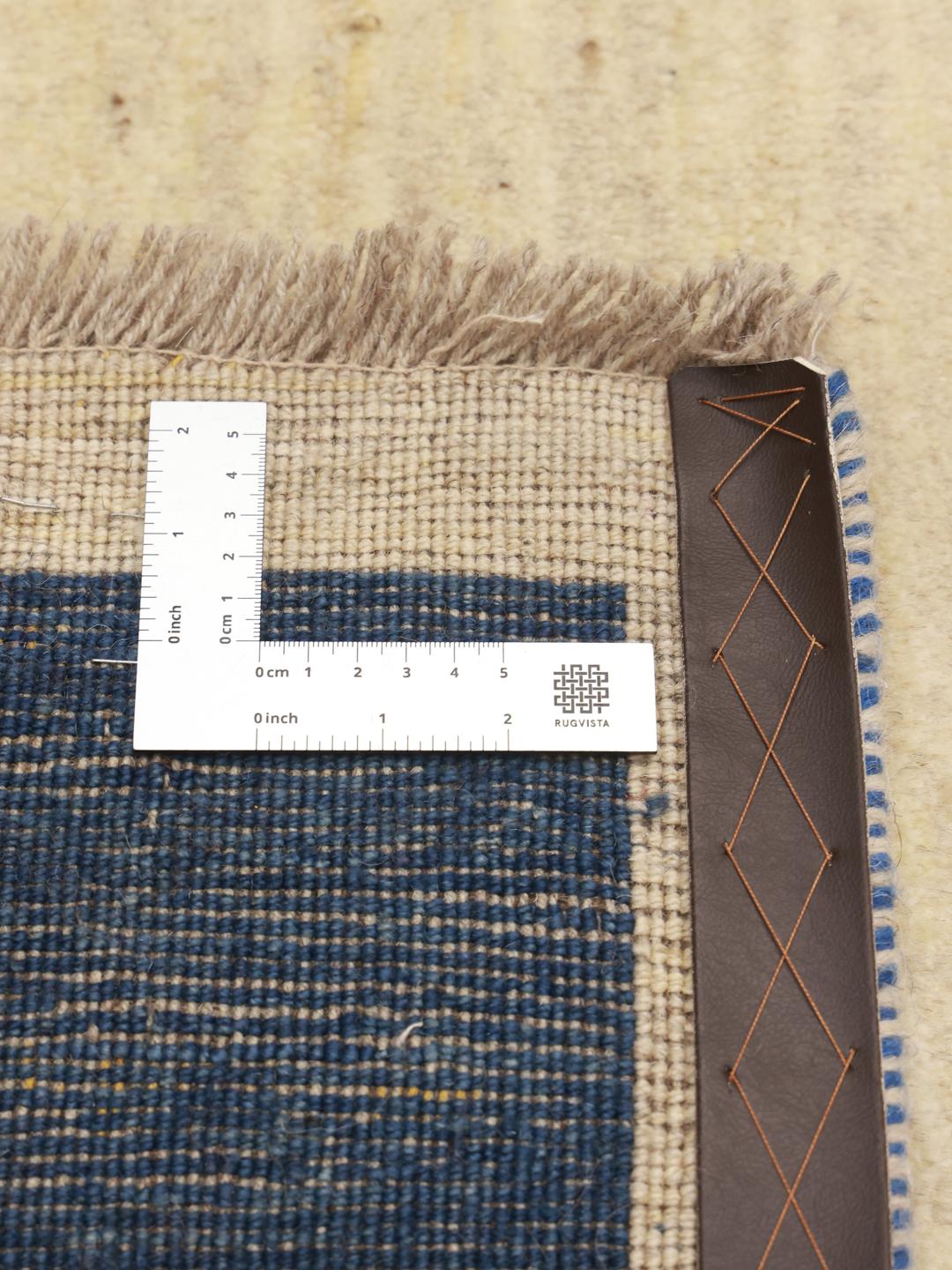 Tapis Gabbeh noué à la main venant du Moyen-Orient avec un champ beige et une bordure bleu foncé.