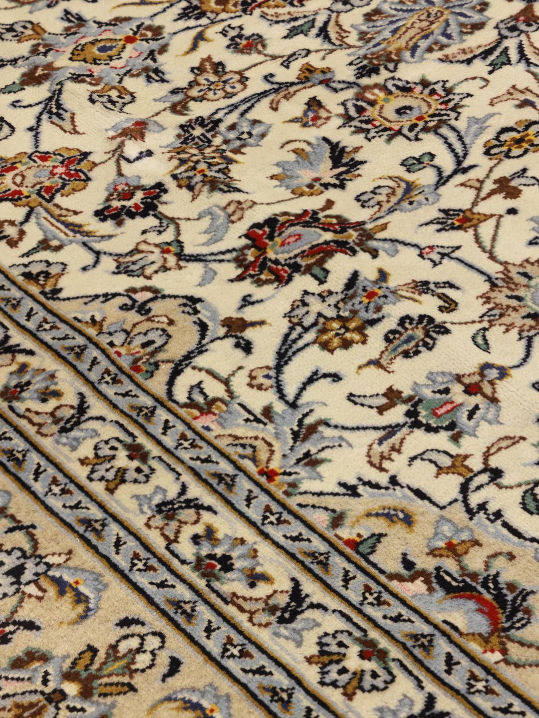 Een handgeknoopt Keshan-tapijt uit het Midden-Oosten in beige tinten met bloemmotieven.