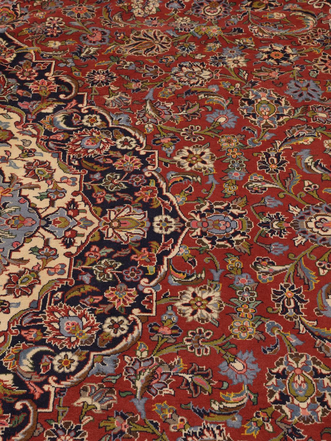 Een handgeknoopt Keshan tapijt uit het Midden-Oosten met een rood en blauw bloemendessin.