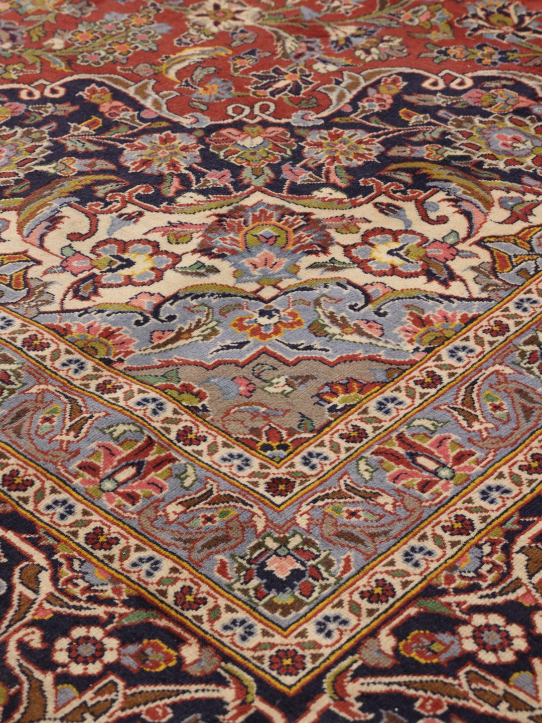 Een handgeknoopt Keshan tapijt uit het Midden-Oosten met een rood en blauw bloemendessin.