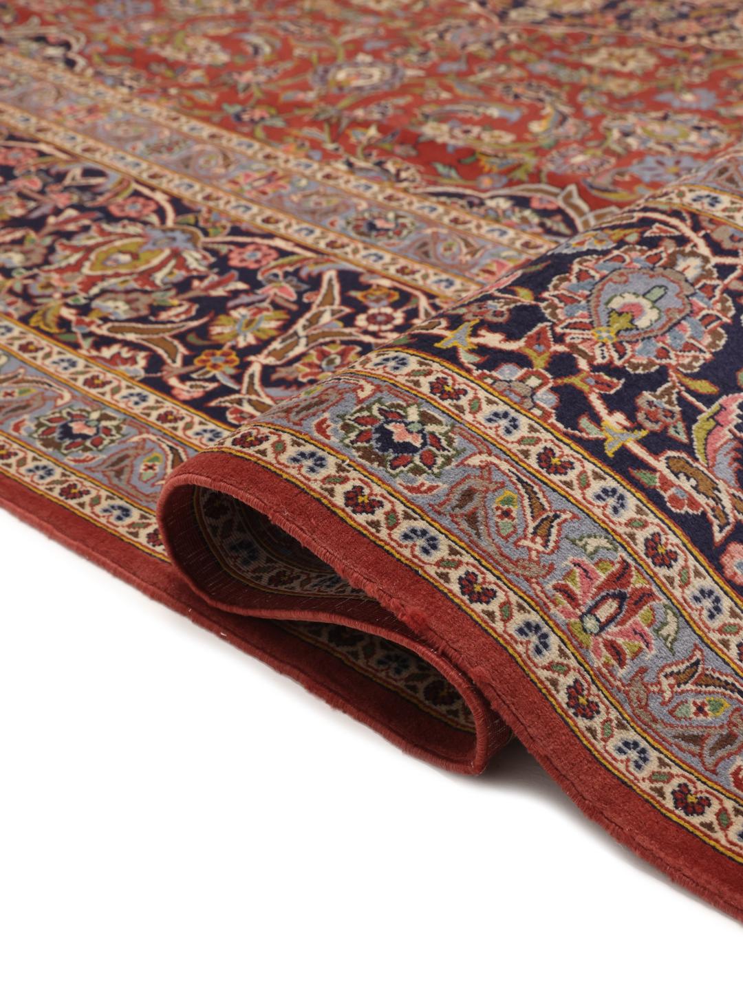 Een handgeknoopt Keshan tapijt uit het Midden-Oosten met een rood en blauw bloemendessin.