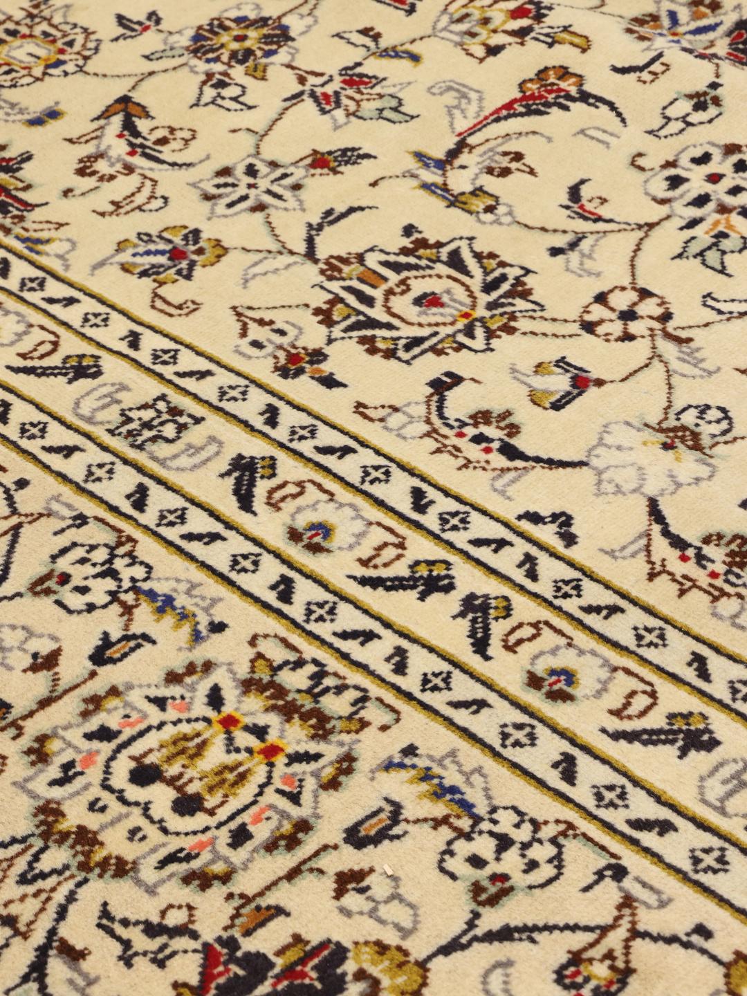 Håndknyttet Keshan-tæppe fra Mellemøsten med beige baggrund og indviklede blomstermotiver.