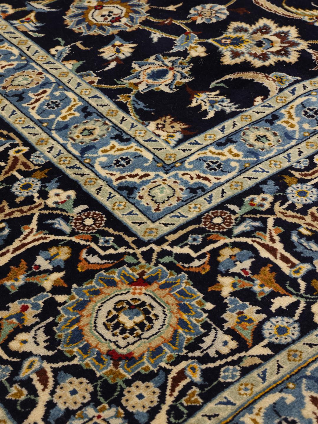 Een groot handgeknoopt Keshan-tapijt uit het Midden-Oosten met een donkerblauw veld en sierlijke bloemenpatronen.
