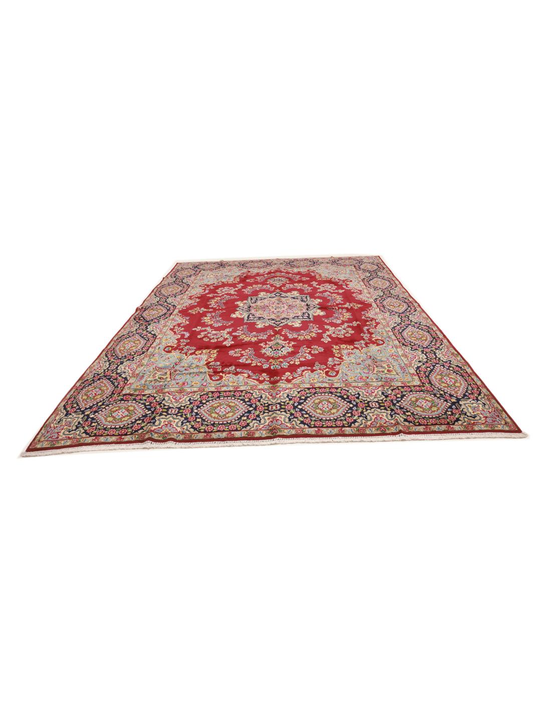 A hand-knotted Kerman rug from the Middle East with a red field and floral patterns.