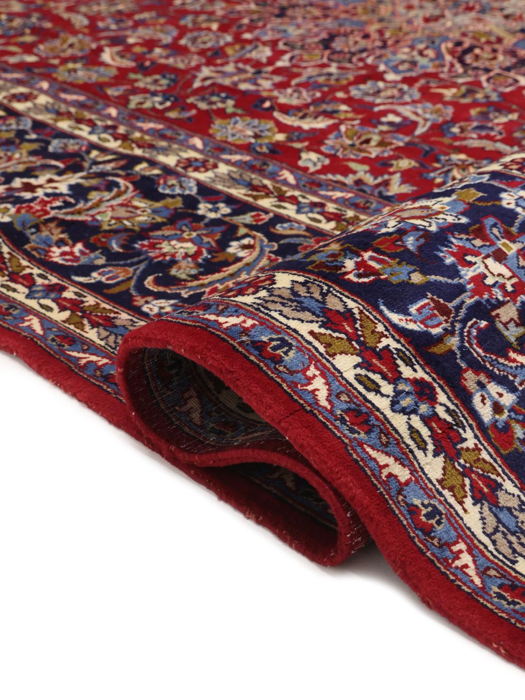 Een groot rechthoekig handgeknoopt Najafabad-tapijt met een rood veld en blauwe bloempatronen uit het Midden-Oosten.