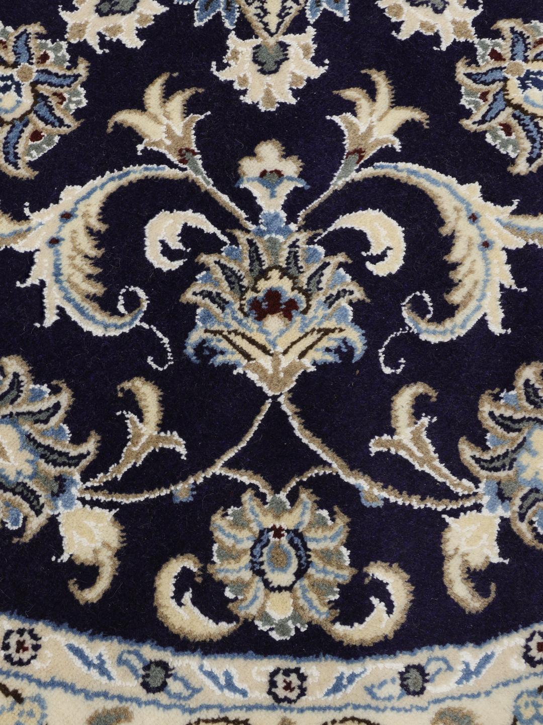 Een prachtig rond handgeknoopt Nain-tapijt uit het Midden-Oosten met bloemmotieven in donkerblauw en beige.