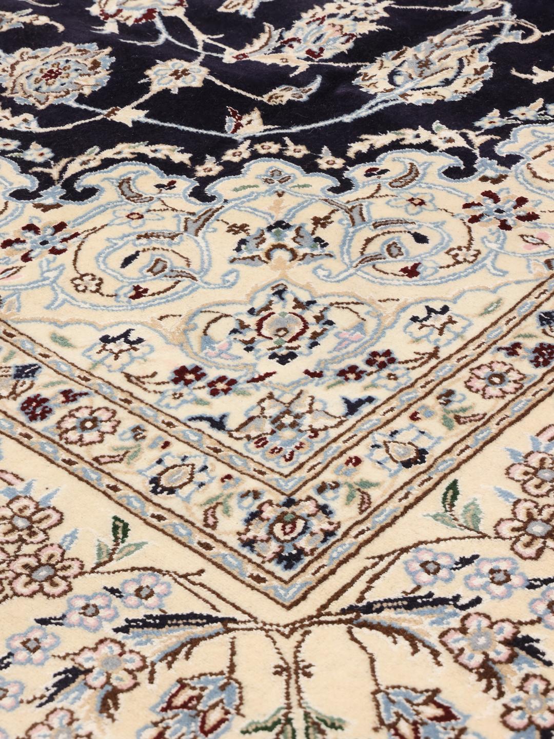 A hand-knotted Nain rug from the Middle East featuring a black field with light floral patterns.
