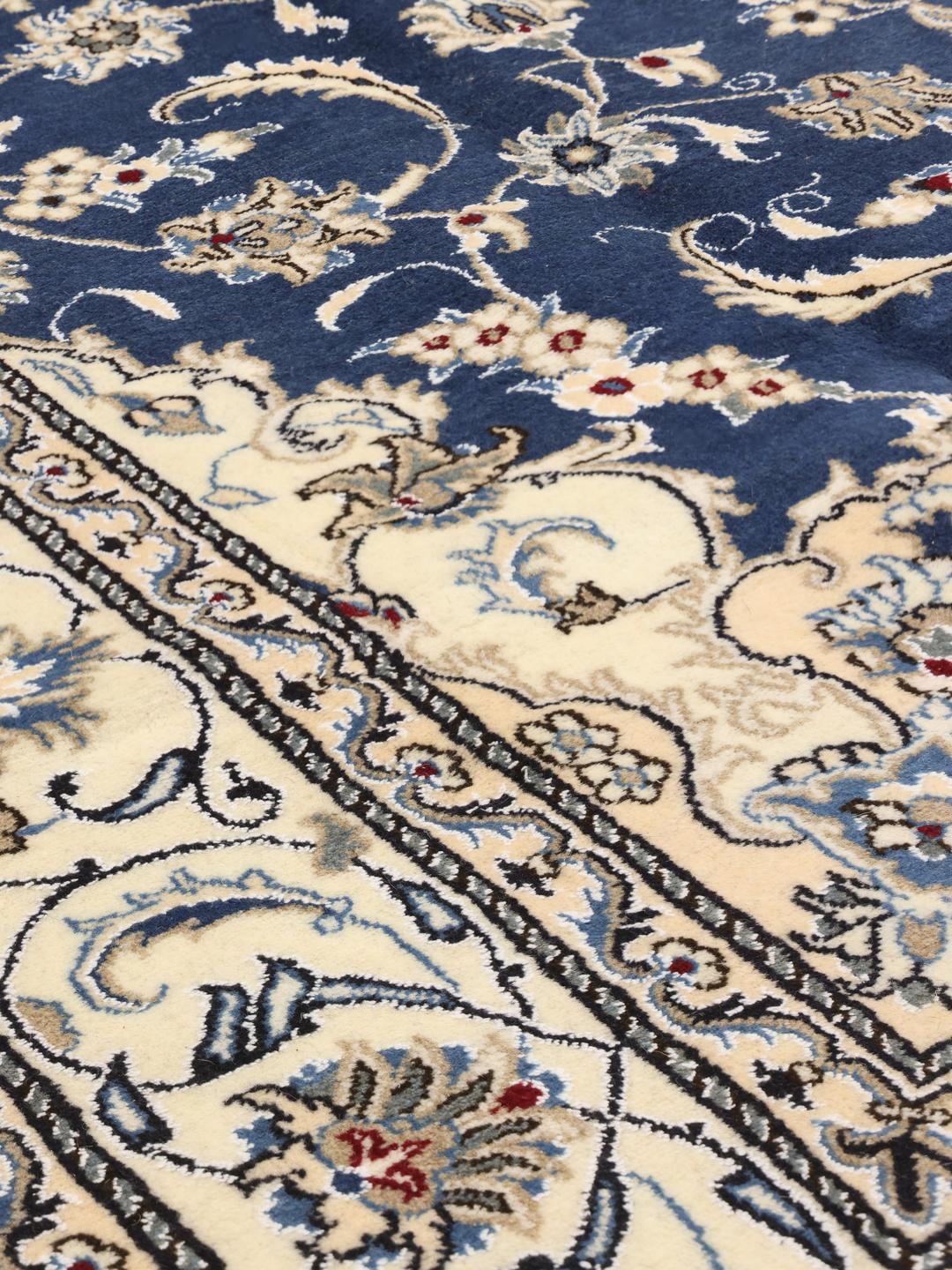 Hand-knotted Nain rug from the Middle East with a deep blue field and floral motifs