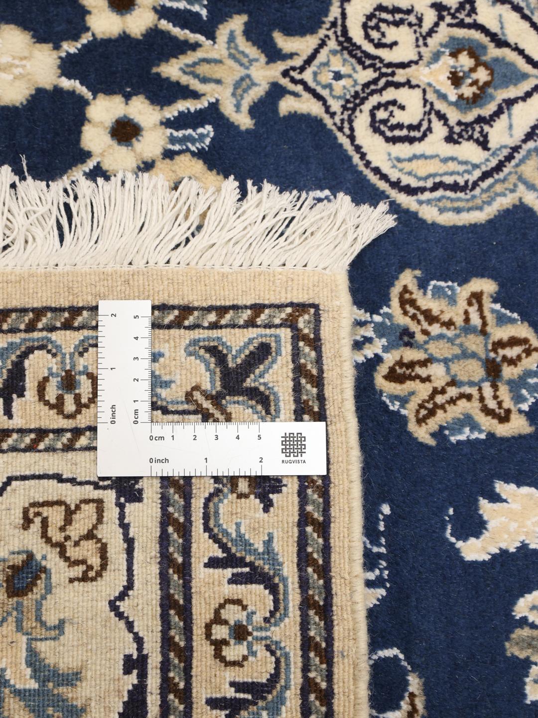 A hand-knotted Nain rug from the Middle East with a deep blue and cream floral pattern.