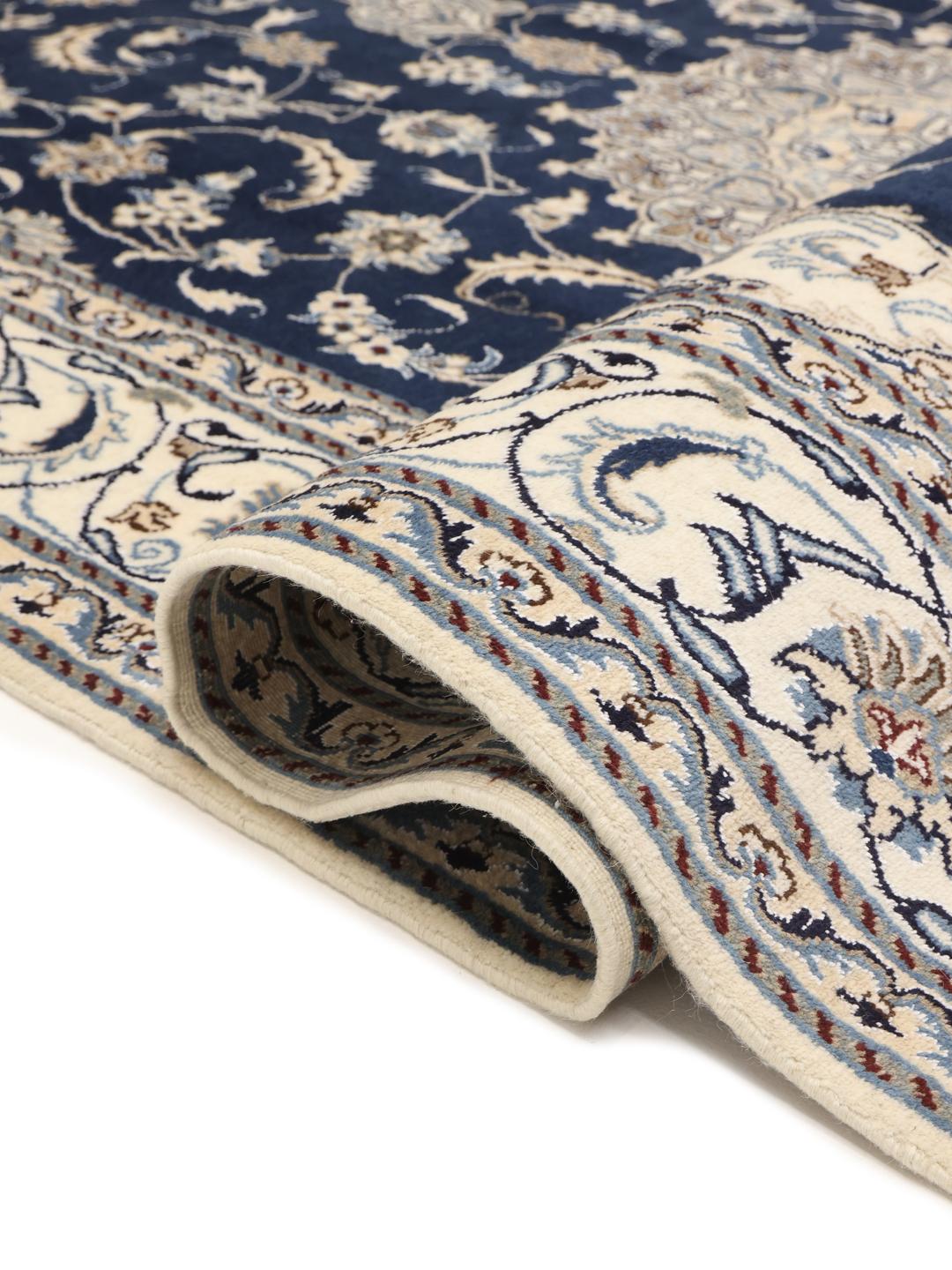 A hand-knotted Nain rug from the Middle East featuring a blue field with floral patterns.