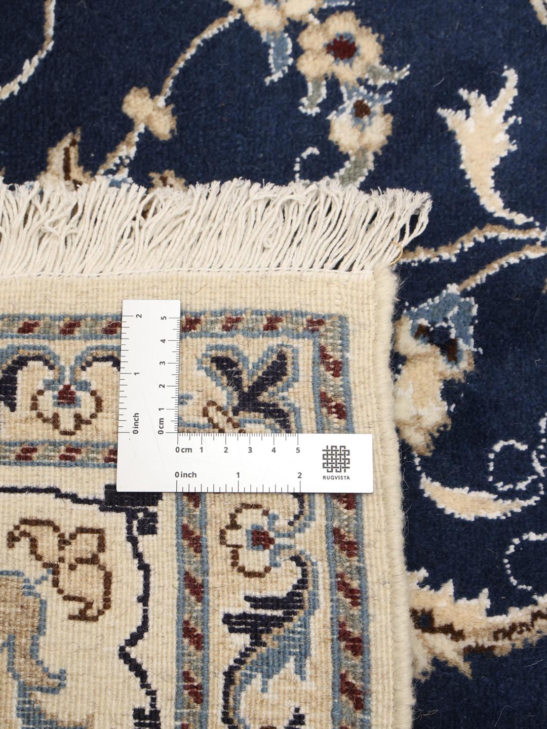 A hand-knotted Nain rug from the Middle East featuring a blue field with floral patterns.