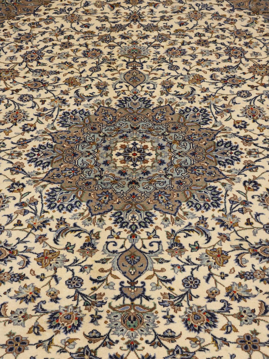 Een groot rechthoekig, met de hand geknoopt Keshan-tapijt uit het Midden-Oosten met een centraal bloemmedaillon op een beige achtergrond.