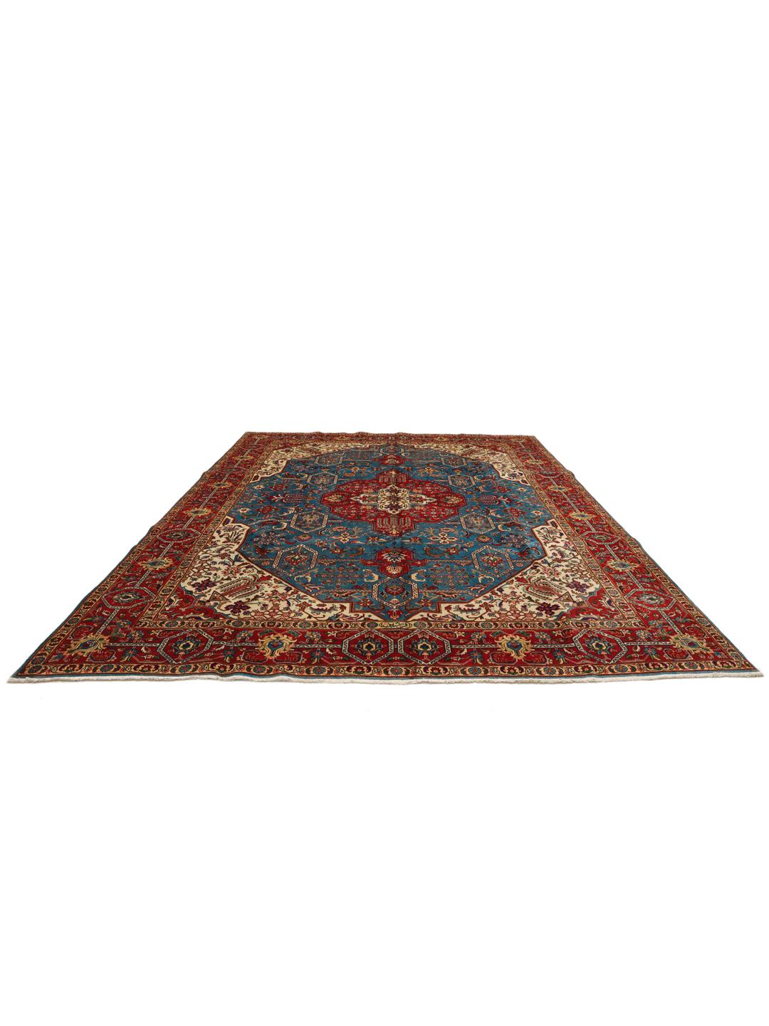 Een groot rechthoekig Tabriz-tapijt uit het Midden-Oosten met een levendig rood en blauwgroen kleurenpalet en sierlijke bloemmotieven.