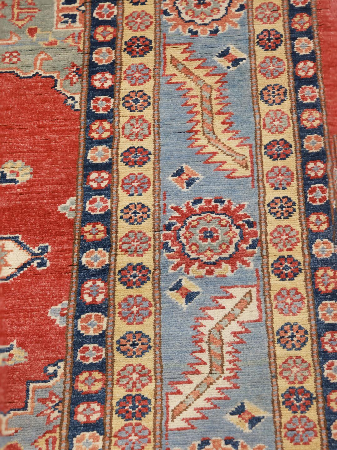 Een handgeknoopt Afghaans Kazak-tapijt met een rood veld en kleurrijke geometrische medaillons.