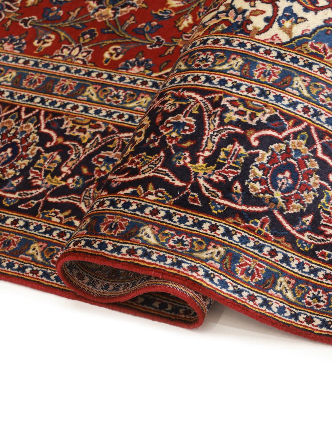 Een met de hand geknoopt Keshan-tapijt uit het Midden-Oosten met een levendig rood en donkerblauw bloemenmedaillonontwerp.