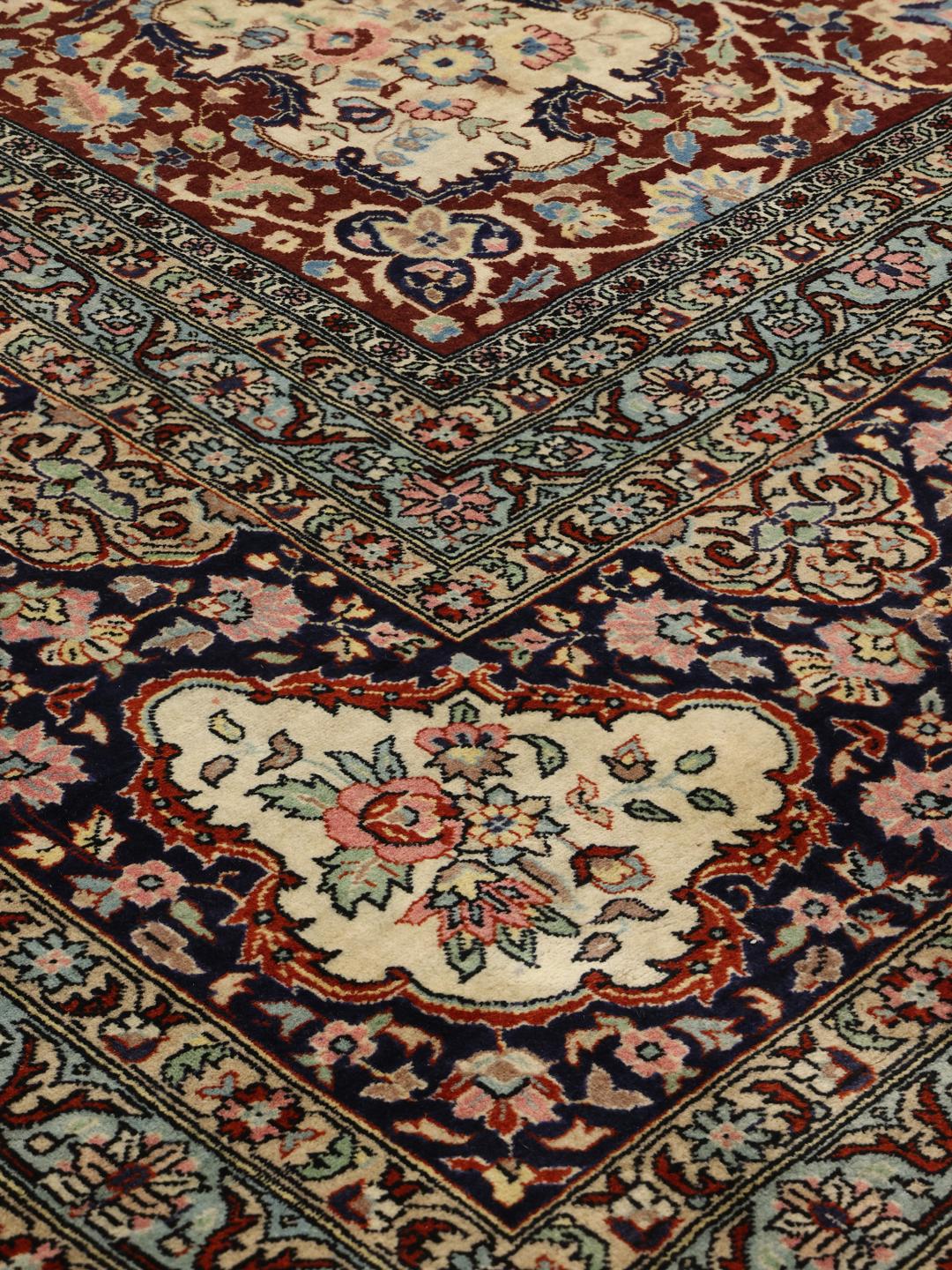 Een groot rechthoekig Tabriz Fine tapijt uit het Midden-Oosten met een donkerrood veld, een centraal medaillon en sierlijke bloemmotieven.