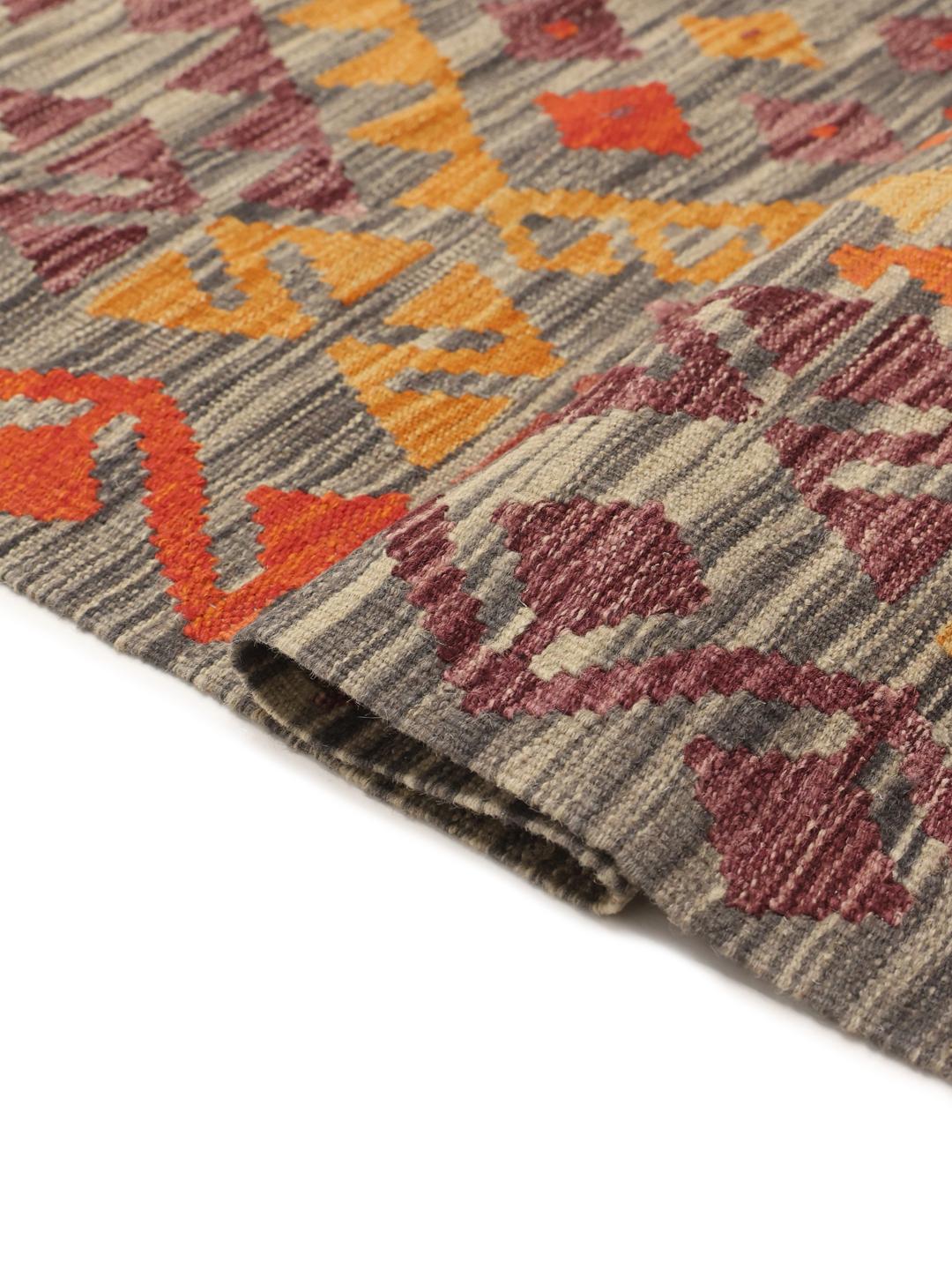 A large rectangular hand-woven Afghan Kelim rug featuring a vibrant geometric pattern in orange, red, and grey tones.