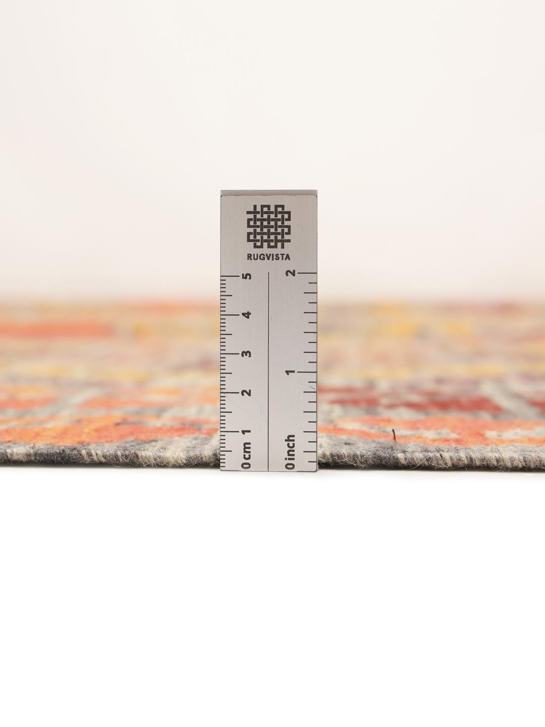 A large rectangular hand-woven Afghan Kelim rug featuring a vibrant geometric pattern in orange, red, and grey tones.
