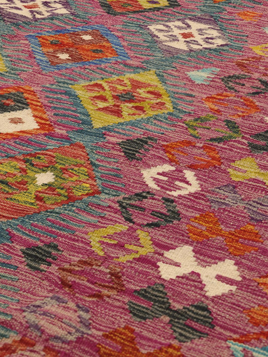 A hand-woven, one-of-a-kind Afghan kelim rug featuring a vibrant, multicoloured geometric pattern.